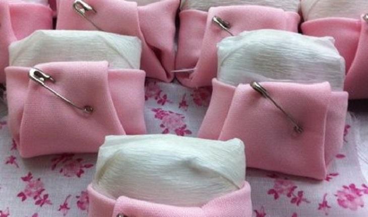 Na foto há alguns bem-nascidos que estão com um tecido ao redor que imita uma fralda. O tecido é da cor rosa e há um alfinete para segurar.