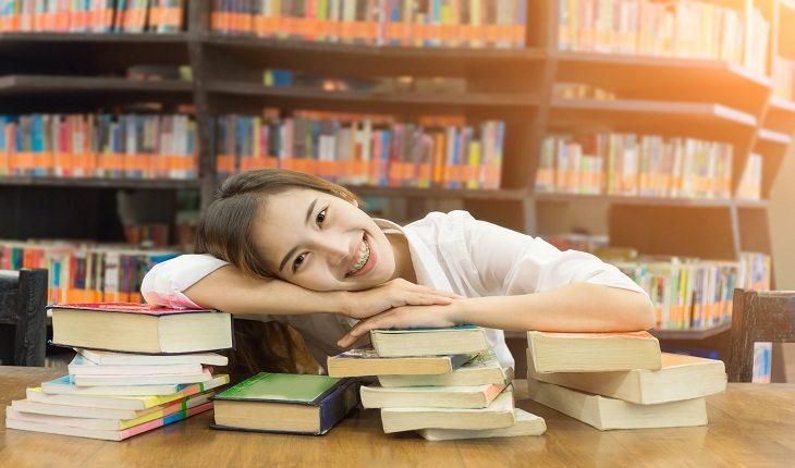 foto de uma moça sorrindo abraçada com livros