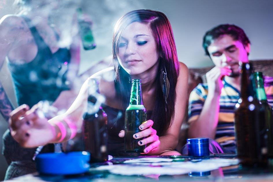 moça em uma festa segurando uma garrafa de cerveja e um cigarro
