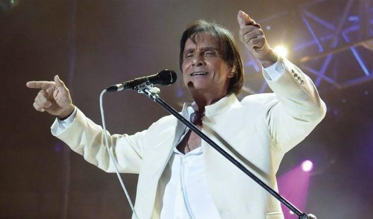Roberto Carlos de braços abertos cantando para a platéia