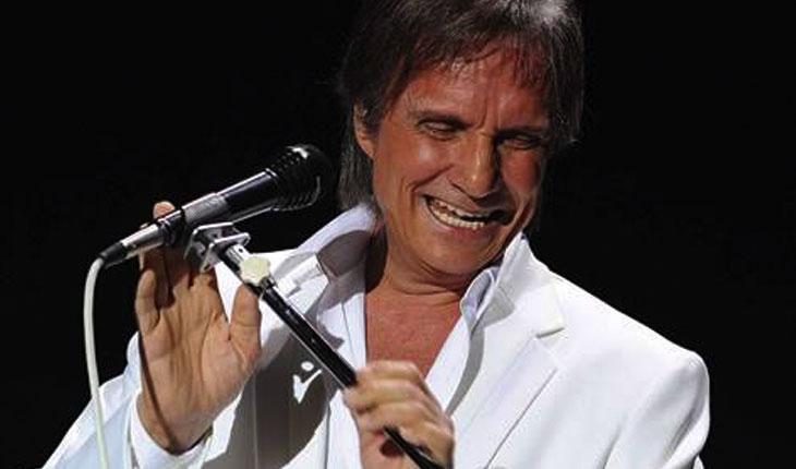 Roberto Carlos sorrindo cantando no microfone