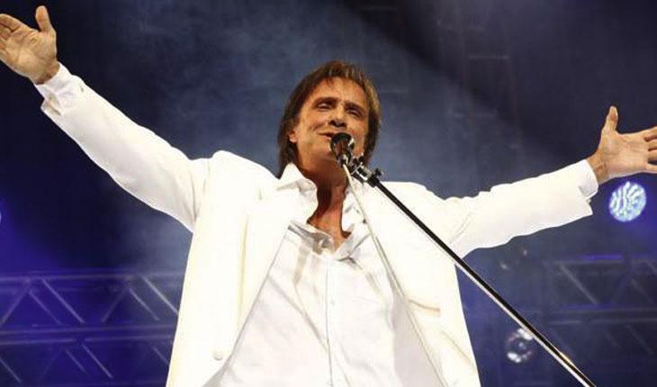 Roberto Carlos de braços abertos cantando para a platéia
