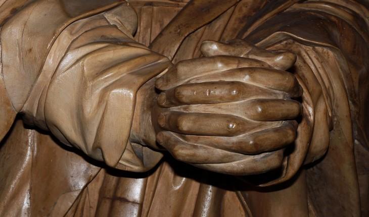 Foto das mãos de uma estátua que está com dedos e as palmas entrelaçadas em sinal de oração. Provérbios de Maio