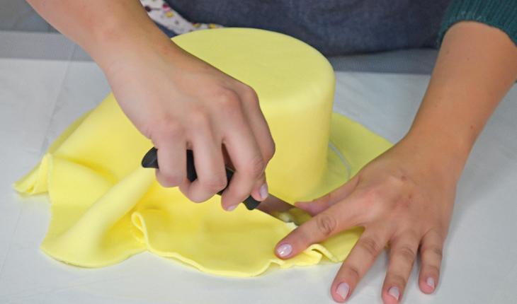Na foto é possível ver uma pessoa cortando o excesso da pasta americana com uma faca