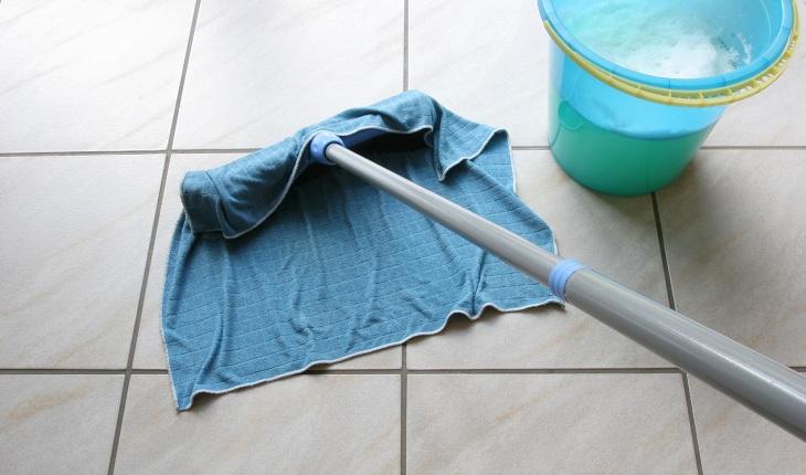 A foto mostra um rodo com pano úmido limpando o chão.