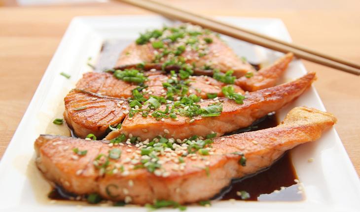 prato com salmão, que está na listra de alimentos funcionais, salpicado com cebolinhas, gergelim e molho shoyu