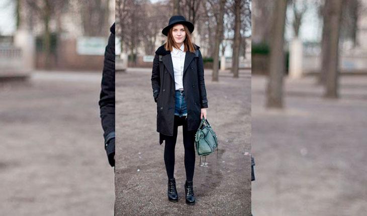 Mulher com short jeans escuro, casaco preto e bota preta
