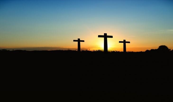 Imagens de 3 cruzes grandes fixas em um morro ao nascer do sol. Orações cotidianas