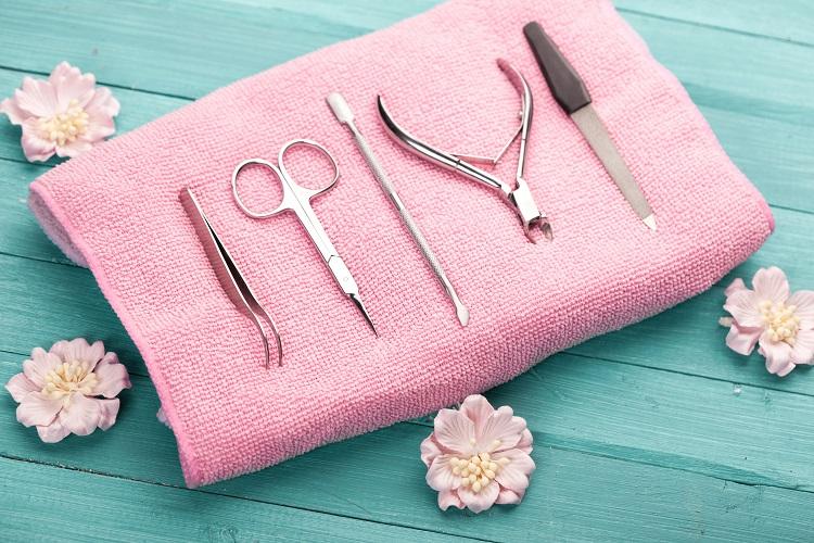 utensílios para fazer unha dispostos sobre uma toalha cor-de-rosa.