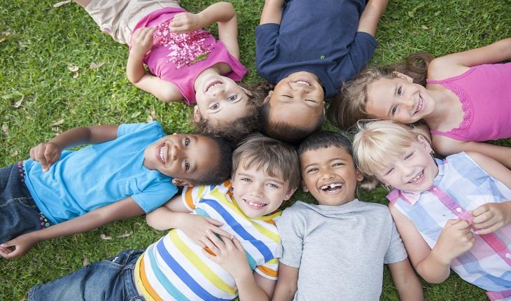 crianças de diferentes etnias sorrindo deitadas num gramado