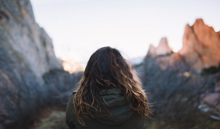 Imagem de mulher agasalhada e de costas para o foco da câmera olhando para as montanhas provérbios da semana