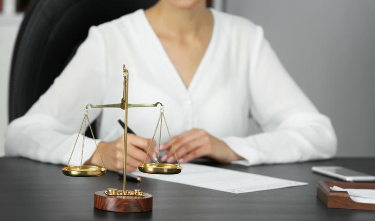 advogada sentada em mesa com simbolo da justiça