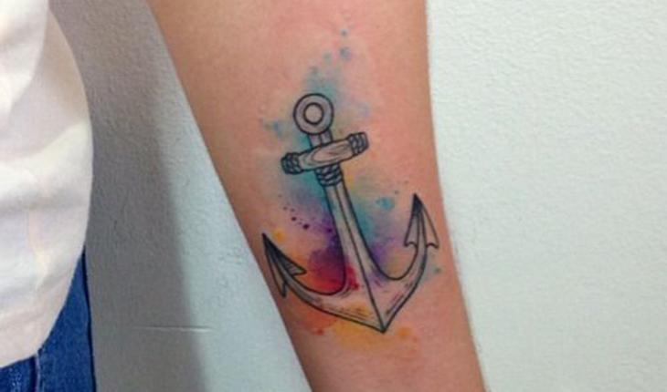 tatuagem de âncora com efeito aquarela no braço
