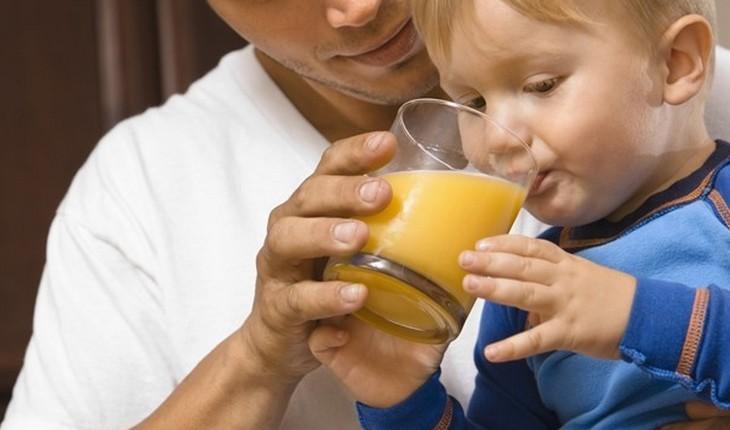 Pai e bebê com copo de suco na mão