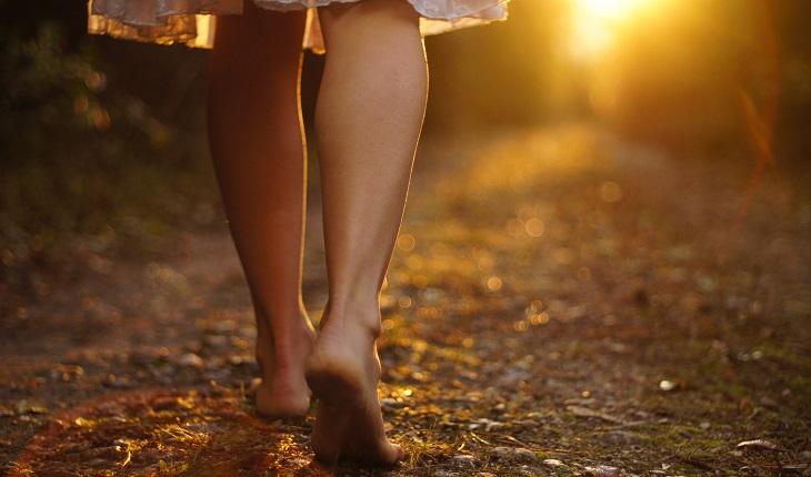 Mulher caminhando descalça em trilha motivada por frases de fé