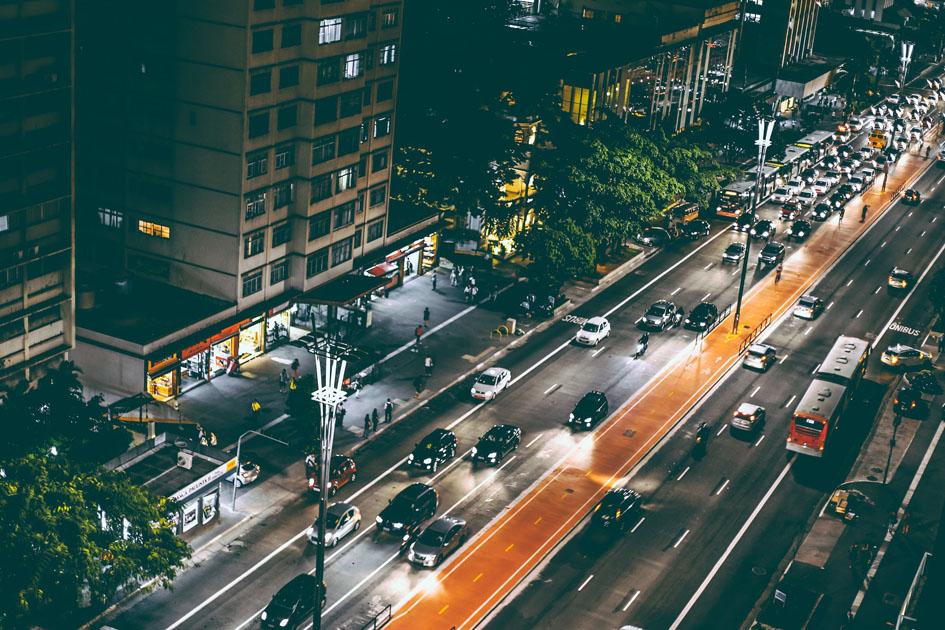 foto de uma avenida de mão dupla, a noite, com muitos carros transitando