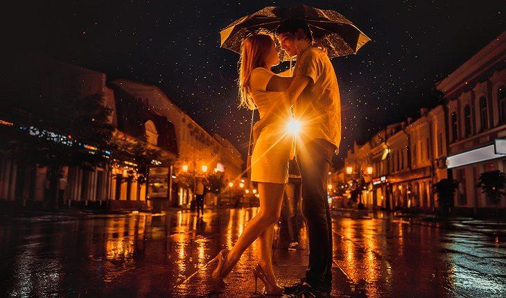 A foto mostra um casal se abraçando na chuva