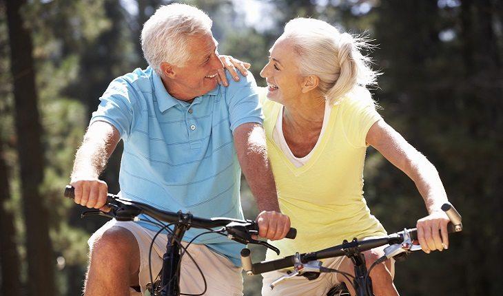 casal de idosos andando de bicicleta e dando risada