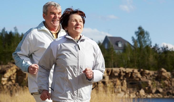 A foto mostra um casal de idosos caminhando ao ar livre. As caminhadas são exercício recomendados na terceira idade