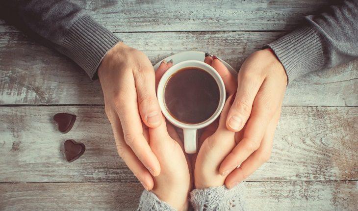 casal de mãos dadas em torno de uma xícara de café