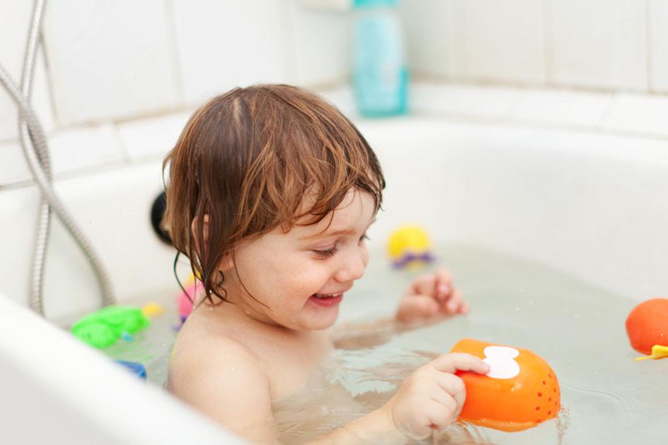criança tomando banho em uma banheira com brinquedos