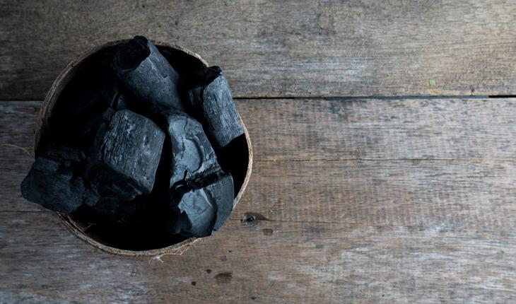 cumbuca com pedaços de carvão sobre uma superfície de madeira