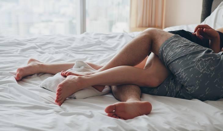 casal deitado na cama com as pernas entrelaçadas