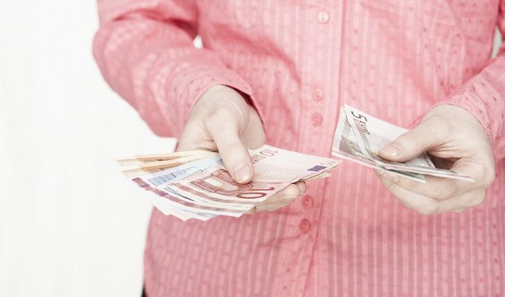mulher de camisa rosa, segurando notas de dinheiro, como calcular o preço de venda