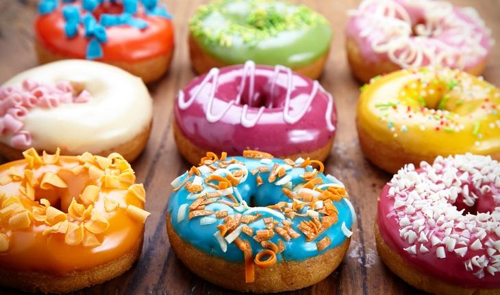 Vários donuts coloridos sobre uma mesa de madeira