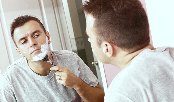 homem branco de cabelo castanho fazendo a barba com espuma