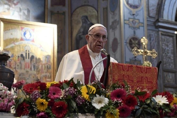 Na imagem, o Papa Francisco está de pé no púlpito enfeitado de flores, fazendo sua homilia em memória dos mártires. 
