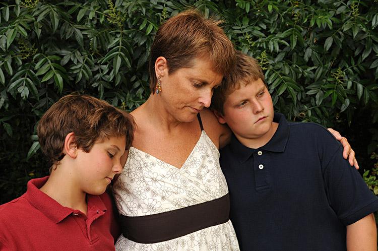 mulher abraçada com dois filhos 
