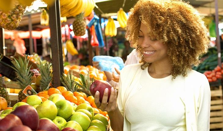 mulher sorrindo escolhendo frutas na feira