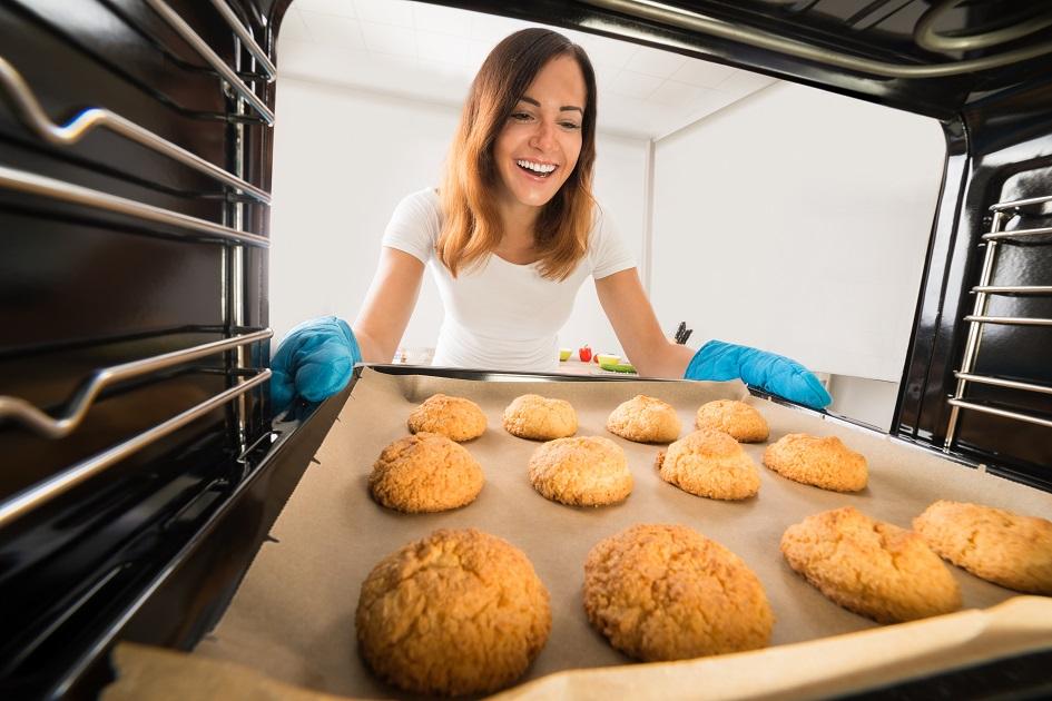 mulher sorrindo tirando cookies do forno