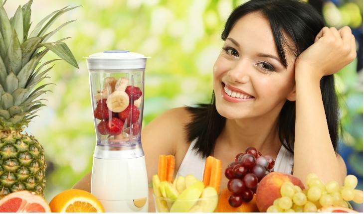 Mulher sorrindo com liquidificador cheio de frutas