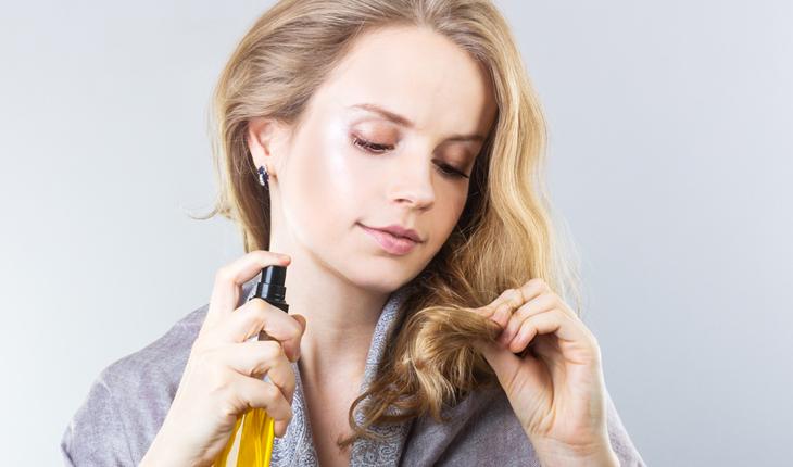 mulher loira aplicando algum produto no cabelo