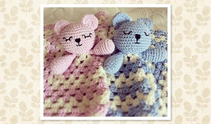 Na foto há duas naninhas em crochê de ursinho, sendo uma rosa e outra azul