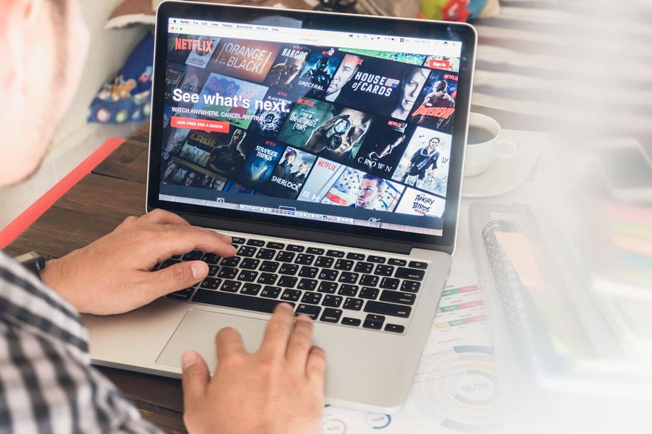 homem mexendo em notebook com tela aberta no site da Netflix e extensão da Netflix Party