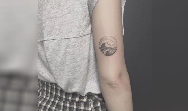 tatuagem de círculo contendo a imagem de uma onda com detalhes em pontilhismo