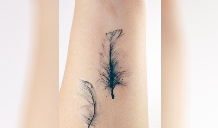 tatuagem de duas penas com efeitos em tons de preto