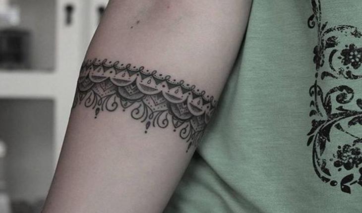 tatuagem em bracelete do que seria uma fita de renda envolvendo o braço