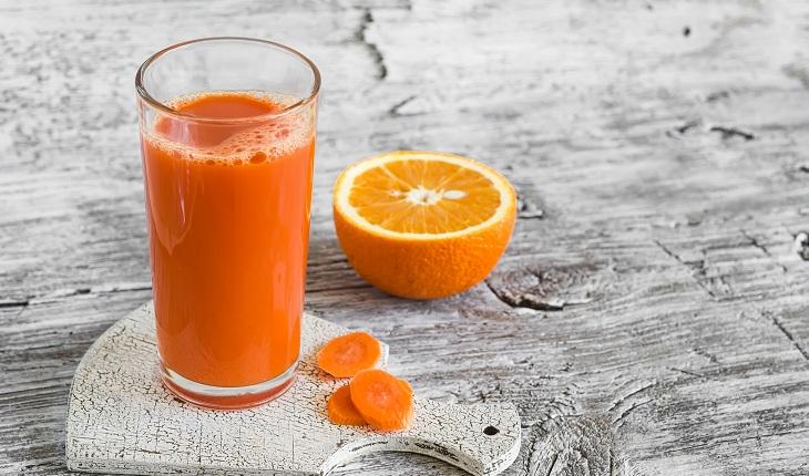Foto do suco de laranja com cenoura em um copo.