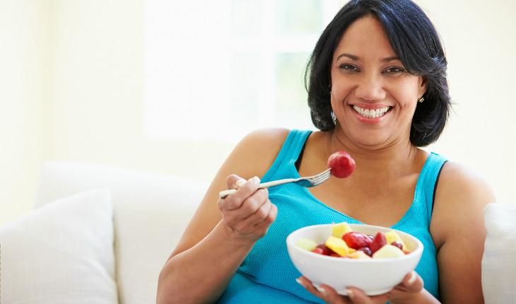 mulher tomando café da manhã com frutas e cereais
