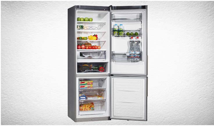 Geladeira cheia com a porta aberta. A geladeira tem o freeze na parte debaixo. A foto tem fundo cinza claro.