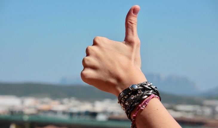 Imagem de uma mão fazendo o sinal de "jóia" com o dedão em representação a pensar positivo