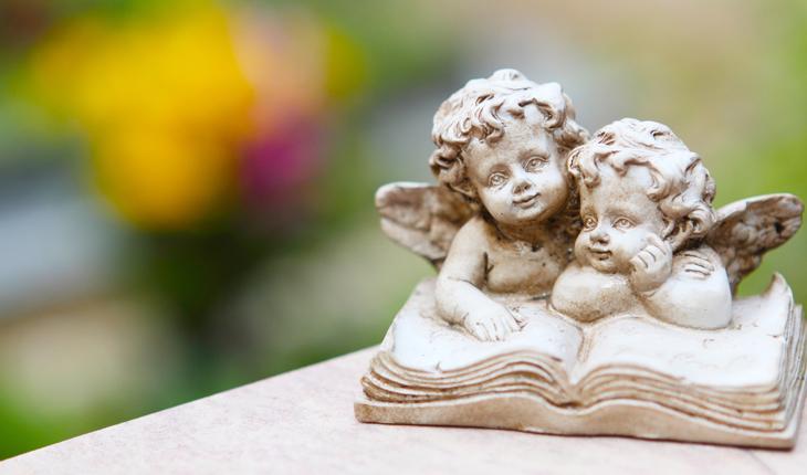 miniatura de dois anjinhos debruçados sobre um livro