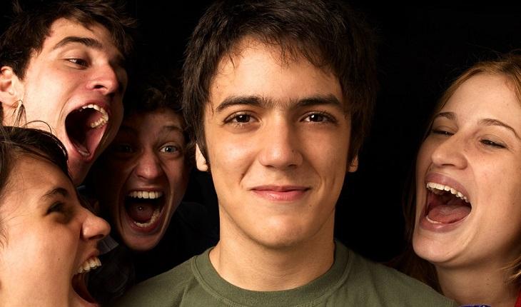 grupo de jovens grita ao redor de adolescente sorrindo em filme brasileiro romântico
