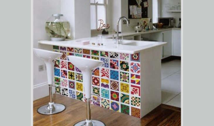 Na foto há uma bancada de cozinha branco, mas sua sustentação é decorado com papel adesivo ou contact que imita azulejos coloridos e decorados.