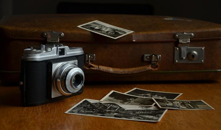 foto de uma câmera antiga, uma maleta marrom e algumas fotos em preto e branco