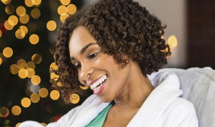 mulher negra sorrindo com cabelo chanel, castanho claro, cacheados
